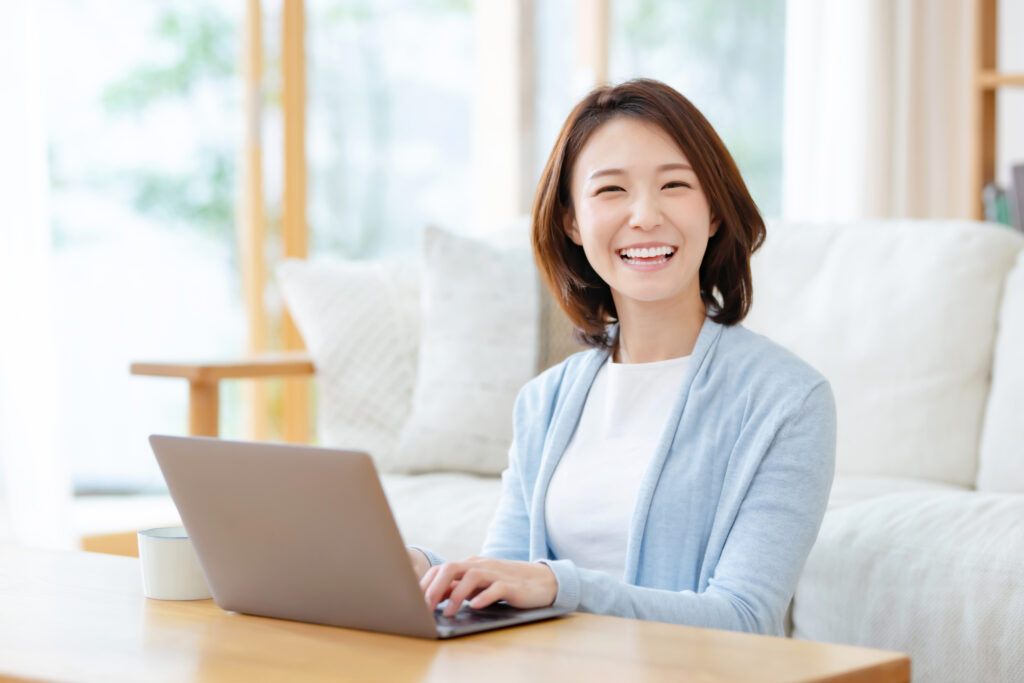 笑顔で自宅でパソコンを開いて仕事をする女性